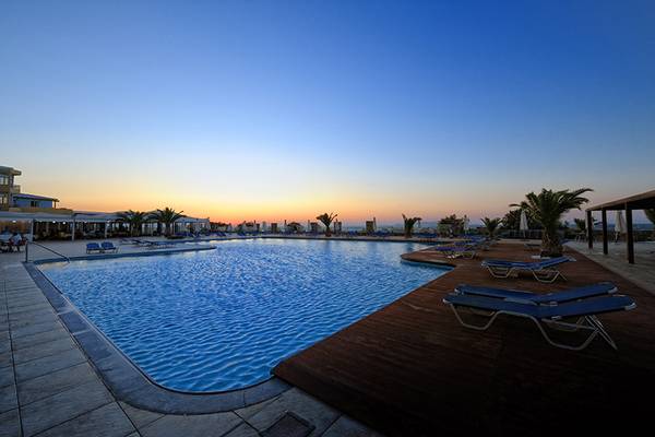 Aphrodite Beach Club Pool bei Sonnenuntergang mit Lounge-Sesseln und Sonnenschirmen