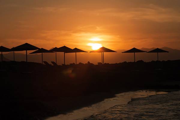Sonnenuntergang am Aphrodite Beach Club mit mehreren Sonnenschirmen am Strand