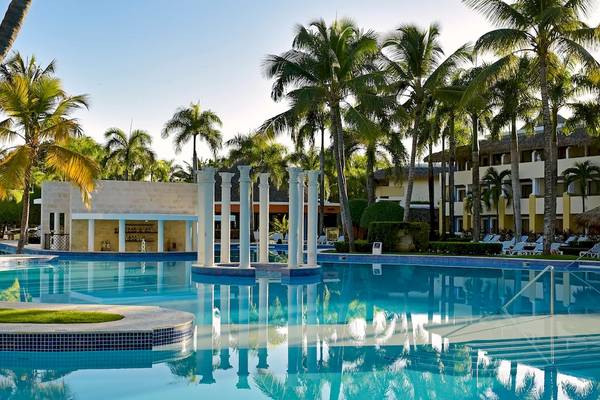 Außenpool des Iberostar Costa Dorada Hotels mit weißen Säulen und umgeben von Palmen und Gebäuden