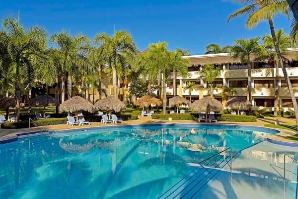 Ein großer Swimmingpool im Iberostar Costa Dorada Hotel, umgeben von Palmen und Sonnenliegen.