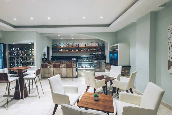 Innenbereich des Iberostar Costa Dorada Hotels mit Bar, Tischen, Stühlen und offenem Eingang.