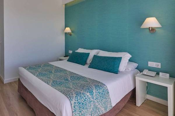 Hotelzimmer im BQ Apolo mit einem Bett, zwei Nachttischen, Wandleuchten und einem Fernseher.