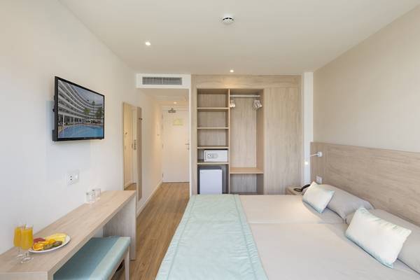 Innenansicht eines Zimmers im HSM Linda Playa Hotel mit Fernseher, Bett und Tisch.