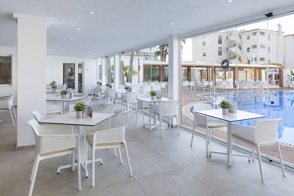 Innenbereich des HSM Linda Playa Hotel Restaurants mit weißen Tischen und Stühlen und Blick auf den Pool.