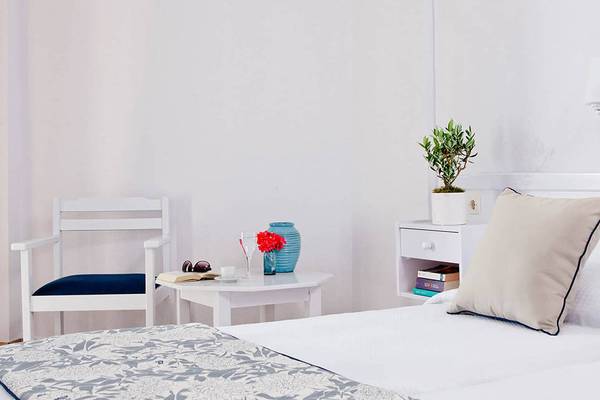 Schlafzimmer im Mrs Chryssana Beach Hotel mit weißem Bett, Beistelltisch und Dekor.