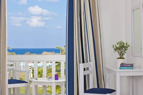 Balkonblick auf das Meer im Mrs Chryssana Beach Hotel mit weißen Möbeln und einer grünen Pflanze.
