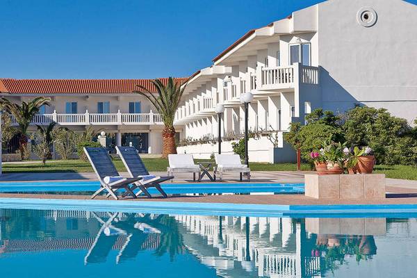 Außenpool des Mrs Chryssana Beach Hotels mit weißen Liegestühlen und Gebäuden im Hintergrund