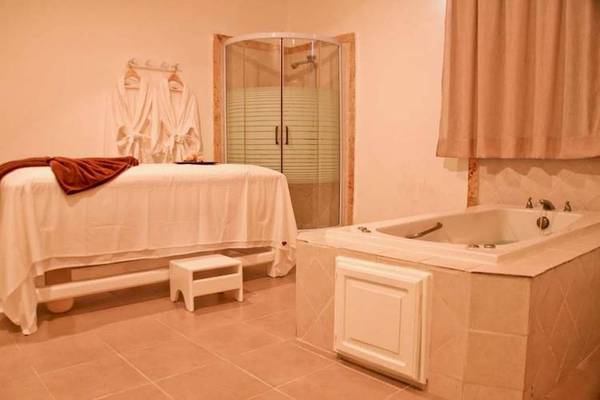 Behandlungsraum im Dreams Flora Resort & Spa mit einem Massagetisch und einer Badewanne.