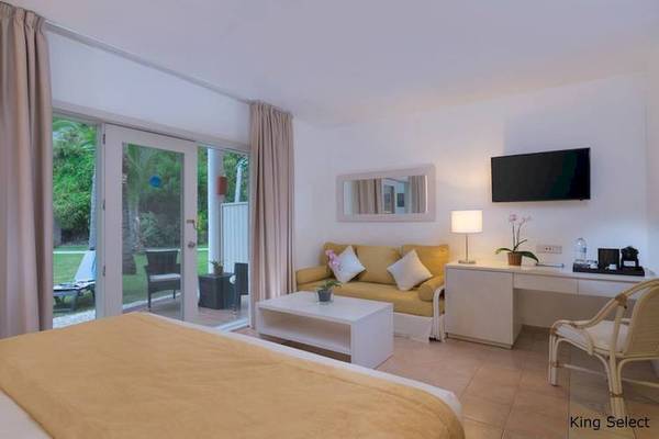 Zimmer im Dreams Flora Resort & Spa mit Bett, Sofa, Schreibtisch und Fernseher.