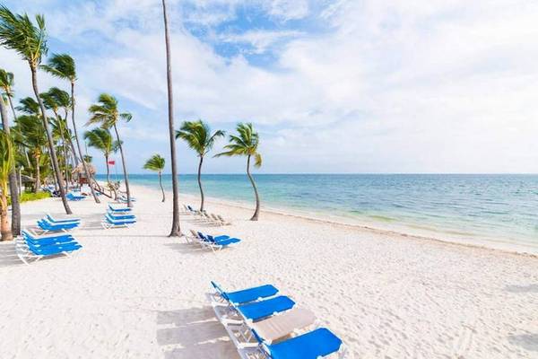 Strand mit weißen Sand, Palmen und blauen Loungesesseln am Dreams Flora Resort & Spa
