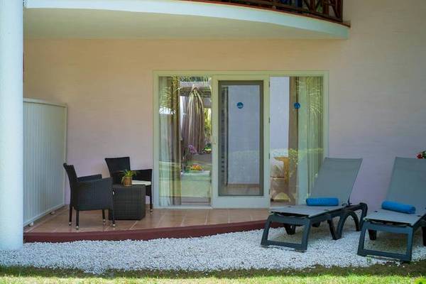 Terrasse der Suite im Dreams Flora Resort & Spa mit zwei Sonnenliegen und einem Tisch.