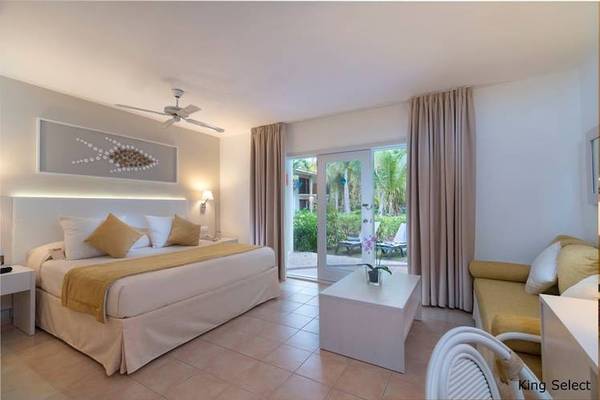 Luxuriöses Zimmer im Dreams Flora Resort & Spa mit Bett, Couch, Tisch und Terrasse.