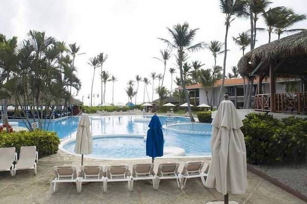 Außenpoolbereich des Dreams Flora Resort & Spa mit Sonnenliegen, Schirmen und tropischen Bäumen