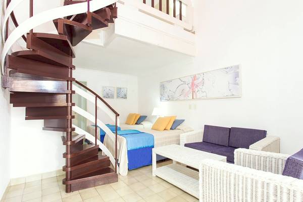 Innenansicht eines Schlafzimmers im Be Live Experience Las Morlas Hotel mit einem Doppelbett, Sofas, Tisch und einer Wendeltreppe.