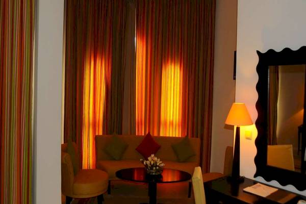 Hotelzimmer im Golden Tulip Taj Sultan mit einem Sofa, einem Tisch, einem Stuhl und einem Spiegel.