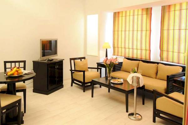 Wohnbereich des Golden Tulip Taj Sultan Hotels mit Sofa, Tisch, Fernseher und Früchten.