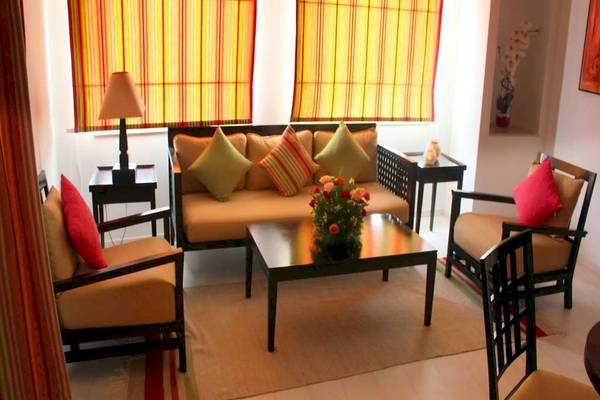 Wohnzimmer im Golden Tulip Taj Sultan Hotel mit Sofa, Tisch, Stühlen und Dekor.