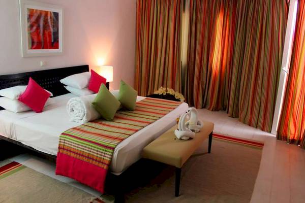 Schlafzimmer im Golden Tulip Taj Sultan Hotel mit einem großen Bett und bunten Kissen.