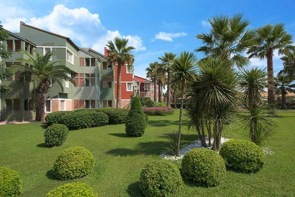 Außenbereich des Megasaray Club Belek Hotels mit gepflegtem Rasen und hohen Palmen