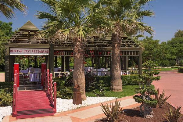Außenansicht des Red Far East Restaurants des Megasaray Club Belek mit rotem Steg und Palmen.
