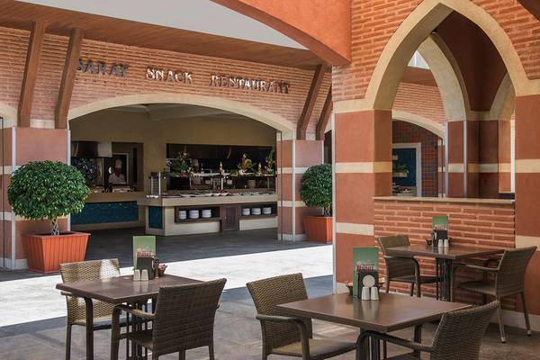 Eingang des Saray Snack Restaurants im Megasaray Club Belek mit Tischen und Stühlen im Freien.