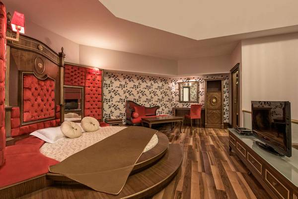 Schlafzimmer im Megasaray Club Belek Hotel mit rundem Bett, rotem Möbeln und Holzboden.