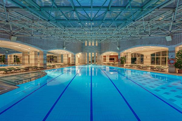 Innenpool des Megasaray Club Belek Hotels mit grünen Liegen und einer Glasdecke