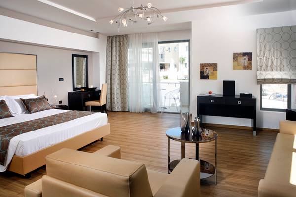 Innenansicht eines eleganten Schlafzimmers im Lesante Classic Luxury Hotel mit Doppelbett, Schreibtisch und Glastisch.