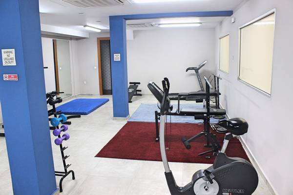 Fitnessraum im Blue Aegean Hotel mit verschiedenen Trainingsgeräten und roter Teppich.