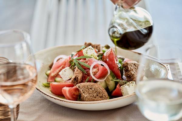 Ein Salat mit Olivenöl wird in einer Schüssel auf einem Tisch serviert.