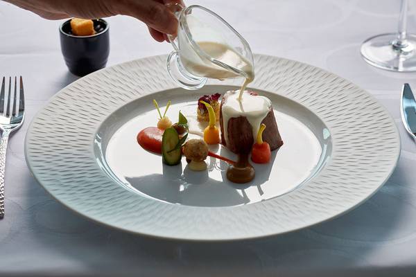 Gedeckter Tisch mit einem Teller, auf dem ein Gericht mit Milchsauce serviert wird.