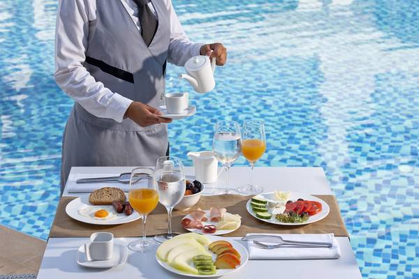 Ein Kellner serviert frisches Frühstück am Pool des Lesante Classic Luxury Hotel & Spa.