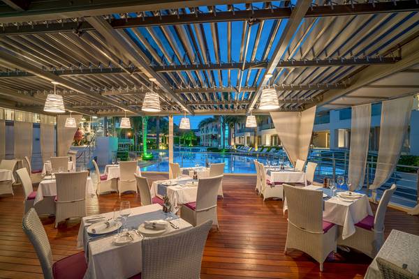 Außenbereich des Restaurants Lesante Classic Luxury Hotel & Spa mit gedeckten Tischen und Blick auf den Pool.