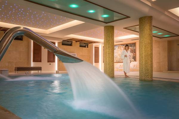 Eine Frau in einem weißen Bademantel steht neben einem Pool im Lesante Classic Luxury Hotel & Spa.