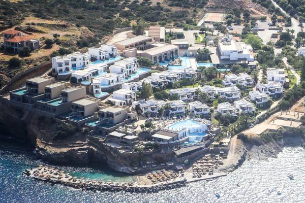 Luftaufnahme des Elounda Village Resort & Spa mit mehreren Pools und Gebäuden am Meer.