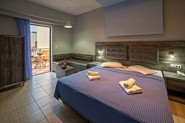 Schlafzimmer im Blue Aegean Hotel mit Doppelbett, Balkonzugang und Nachttischen.