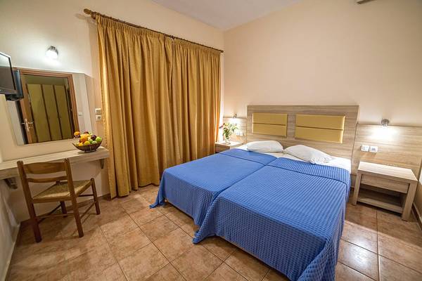 Doppelbett-Zimmer im Blue Aegean Hotel & Suites mit zwei Betten, Tisch, Stuhl und Spiegel.