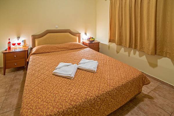 Schlafzimmer im Blue Aegean Hotel mit Bett, Nachttischen, Weingläsern und Früchten.