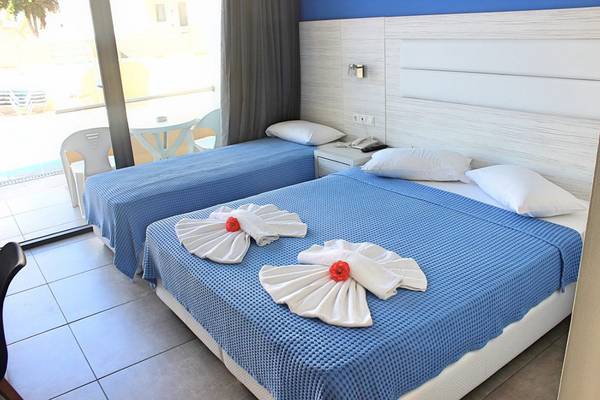 Zwei Betten im Zimmer des Blue Aegean Hotel & Suites mit blauen Decken und weißen Kissen.