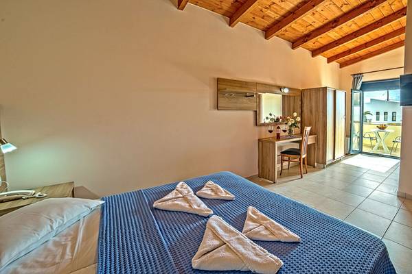Schlafzimmer im Blue Aegean Hotel mit einem Bett, einer Kommode und einer offenen Tür.