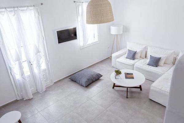 Wohnzimmer des Pietra E Mare Mykonos Hotels mit weißem Sofa, Tisch, Lampen und Fernseher.