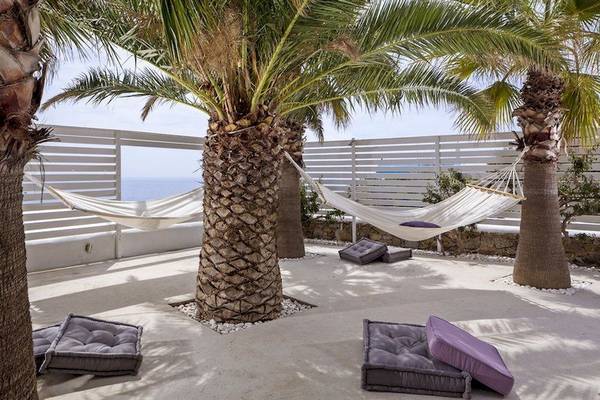 Terrasse im Pietra E Mare Mykonos mit zwei weißen Hängematten und Palmen