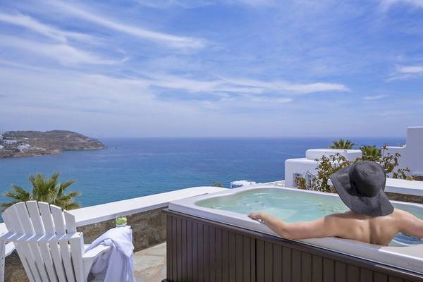Person genießt Whirlpool auf Hotelbalkon mit Blick auf den Ozean