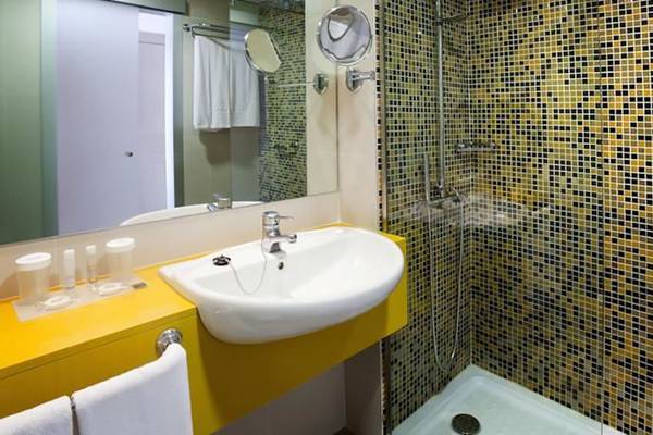 Ein Badezimmer mit einer gelben Theke, einem Waschbecken, einem Spiegel und einer gefliesten Duschkabine.