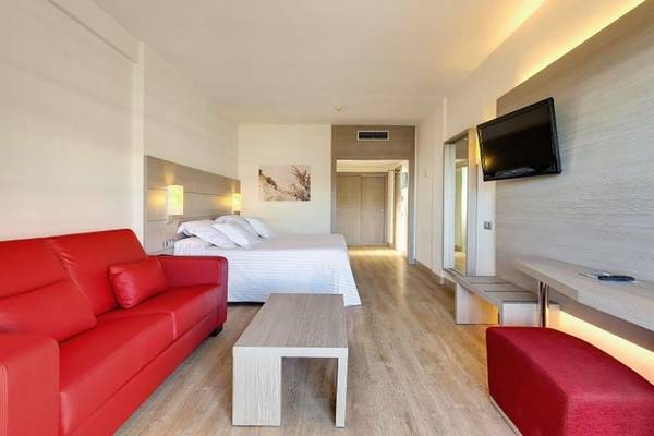 Hotelzimmer im Barcelo Margaritas mit rotem Sofa, Tisch, Bett und Fernseher.