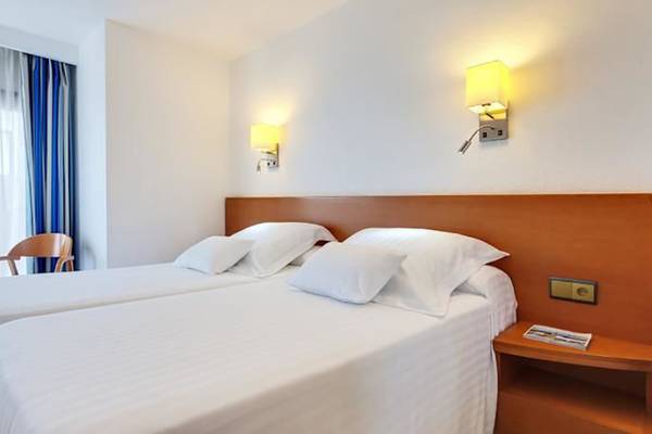 Doppelzimmer im Barcelo Margaritas Hotel mit zwei Betten, weißen Kissen, Nachttischen und Wandlampen.