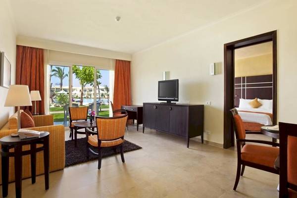 Wohnbereich des DoubleTree by Hilton Sharks Bay Resort mit Fernseher, Möbeln und Blick auf den Pool.
