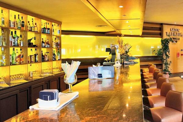 Innenansicht der Bar im Barcelo Fuerteventura Mar Hotel mit Bartheken, gefüllten Flaschen und Lederstühlen.