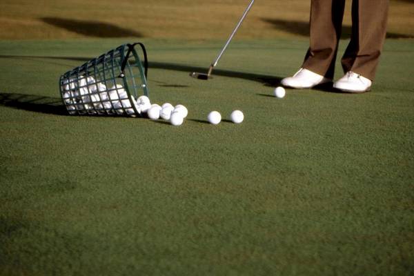 Golfplatz mit Golfer, Golfschläger, Golfbällen und Golfkorb.