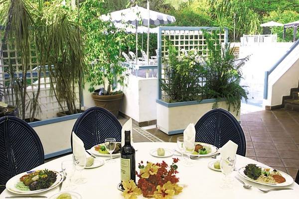 Essen im Garten des Karibea Sainte Luce Hotels mit Tisch, Tellern und Pflanzen.